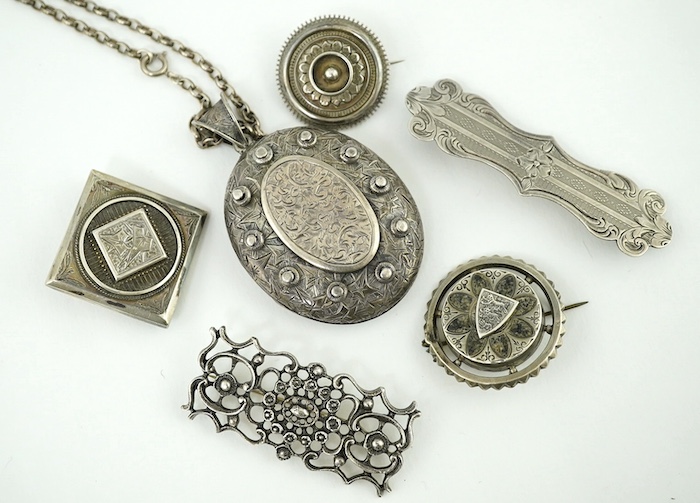 An oval engraved white metal enclosed locket and chain and five assorted white metal brooches. Condition - fair